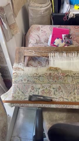 Établi de restauration avec un tapis en cours de reprise des franges.