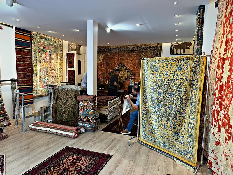 Kilims et tapis anciens empilés dans la boutique.